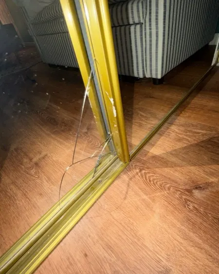 A mirrored sliding door with cracked glass at floor level